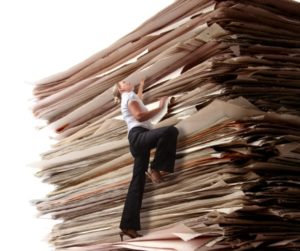 Business woman climbing a pile of files.